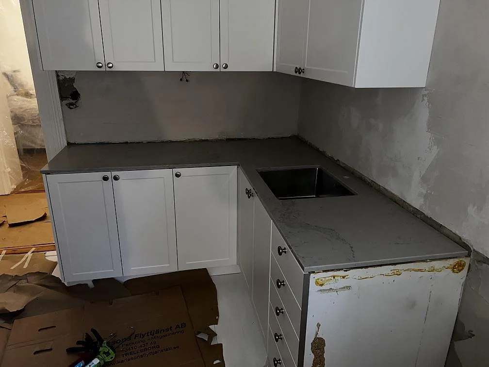 Köksbänkskiva i Caesarstone Noble Grey, polerad, med underlimmad rostfri diskho i ett L-format kök i Helsingborg.