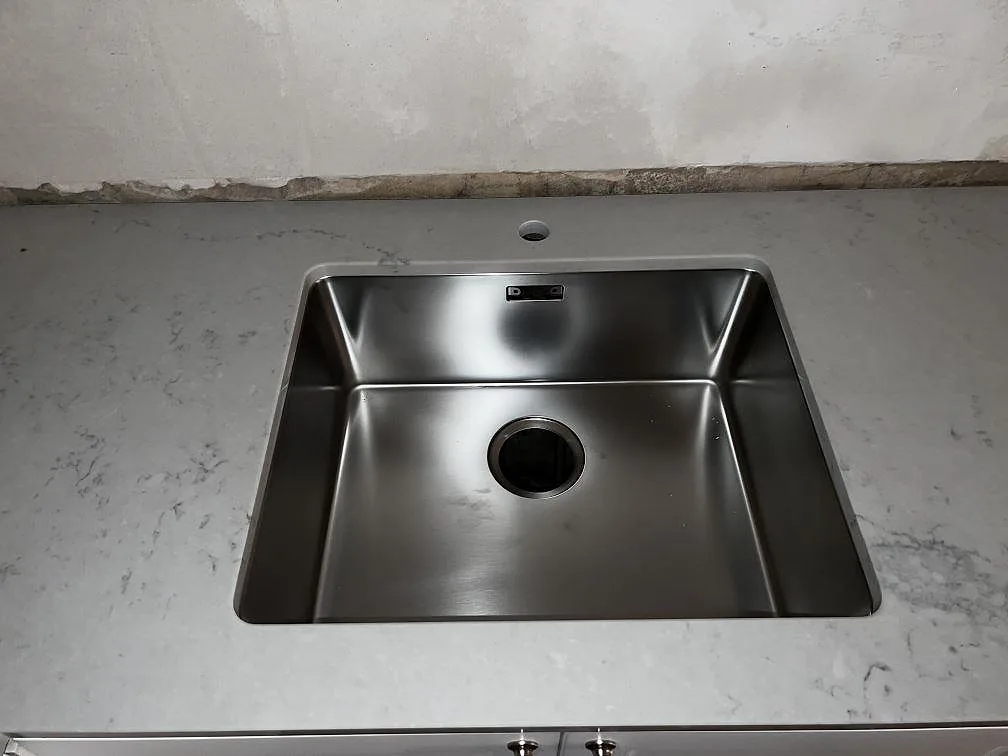 Underlimmad rostfri diskho i en polerad köksbänkskiva av Caesarstone Noble Grey i Helsingborg.