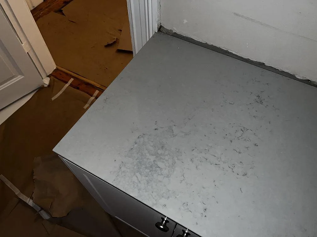 Ändstycke av köksbänkskiva i polerad Caesarstone Noble Grey vid dörröppning i ett kök i Helsingborg.