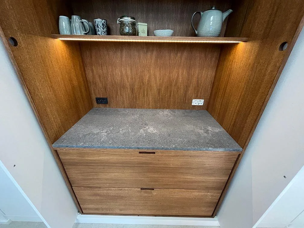 Bänkskiva i Caesarstone Rugged Concrete, matt betonglik komposit, i en träklädd nisch med öppen hylla i Kastrup.