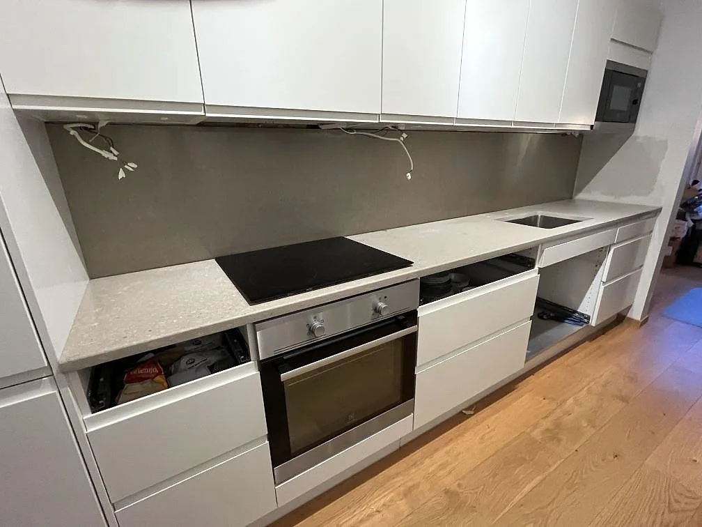 Köksbänkskiva i polerad Caesarstone Shitake med underlimmad diskho och spishäll i ett kök under montering i Bromma.