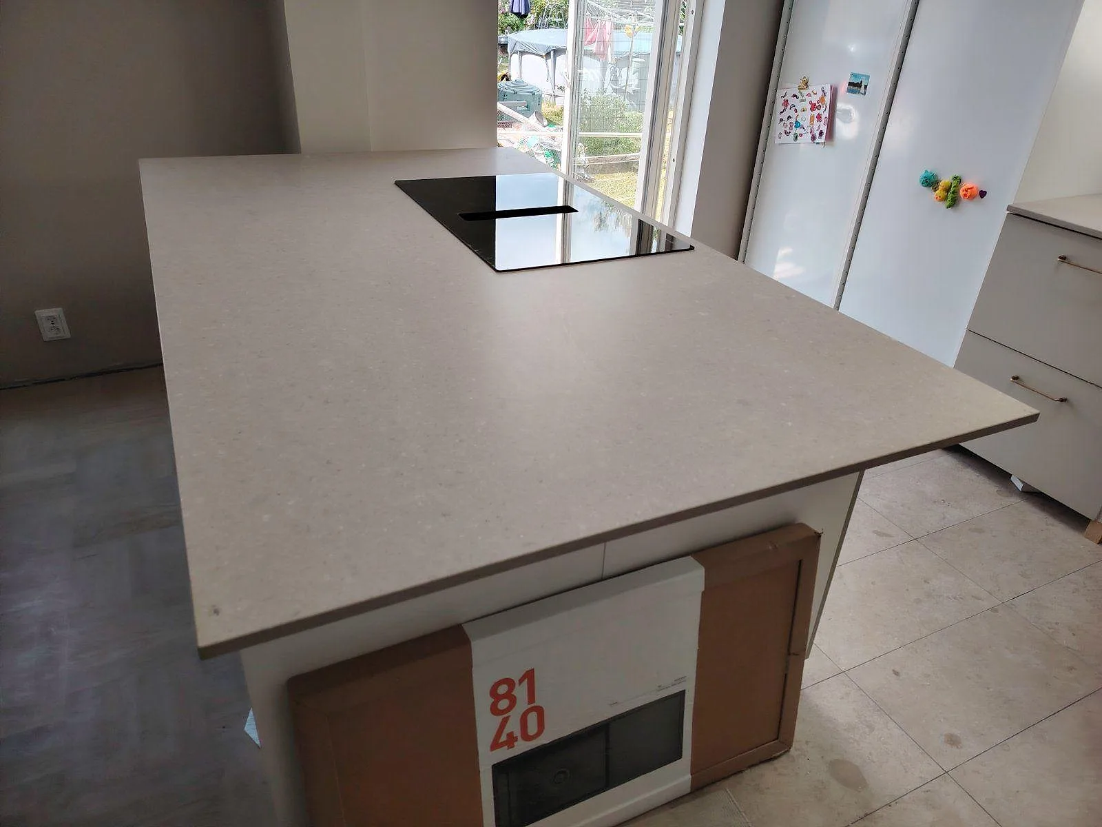 Köksbänkskiva i matt Caesarstone Shitake komposit med svart induktionshäll på en kökshalvö i Enskede.