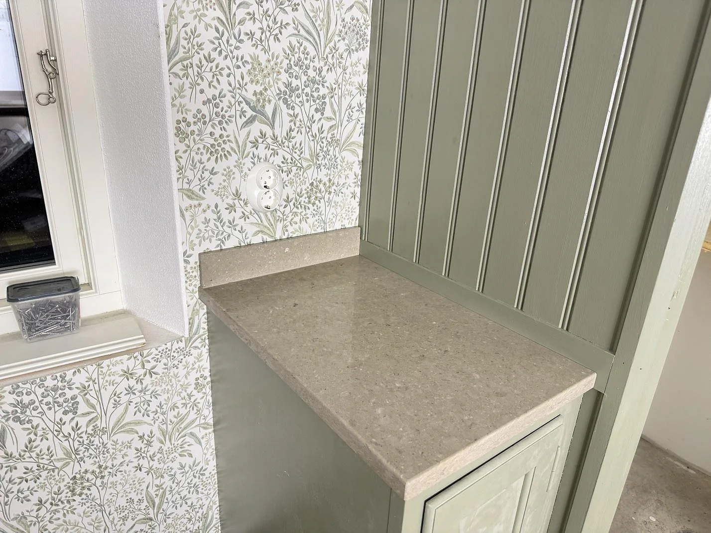 Kort bänkparti i Caesarstone Shitake, polerad gråbeige kvartskomposit, med uppvikt stänkkant vid fönster och panel i Hörby.