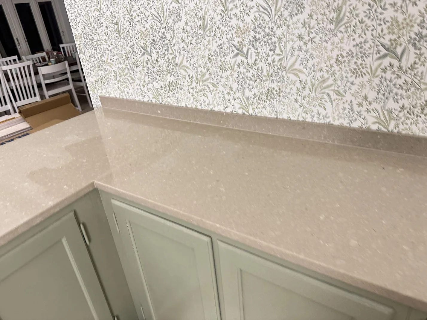 Närbild på L-format hörn i Caesarstone Shitake köksbänkskiva, polerad gråbeige komposit med synlig kantprofil i Hörby.