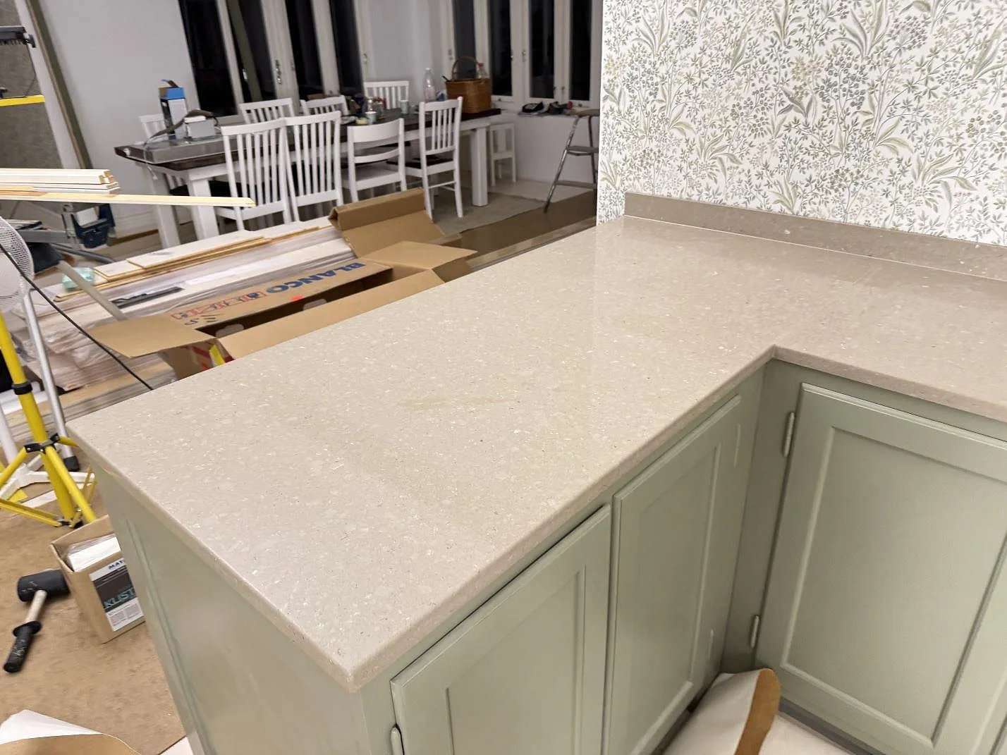 Bred vy av Caesarstone Shitake köksbänkskiva i polerad komposit med halvö och monteringsmaterial runt köket i Hörby.