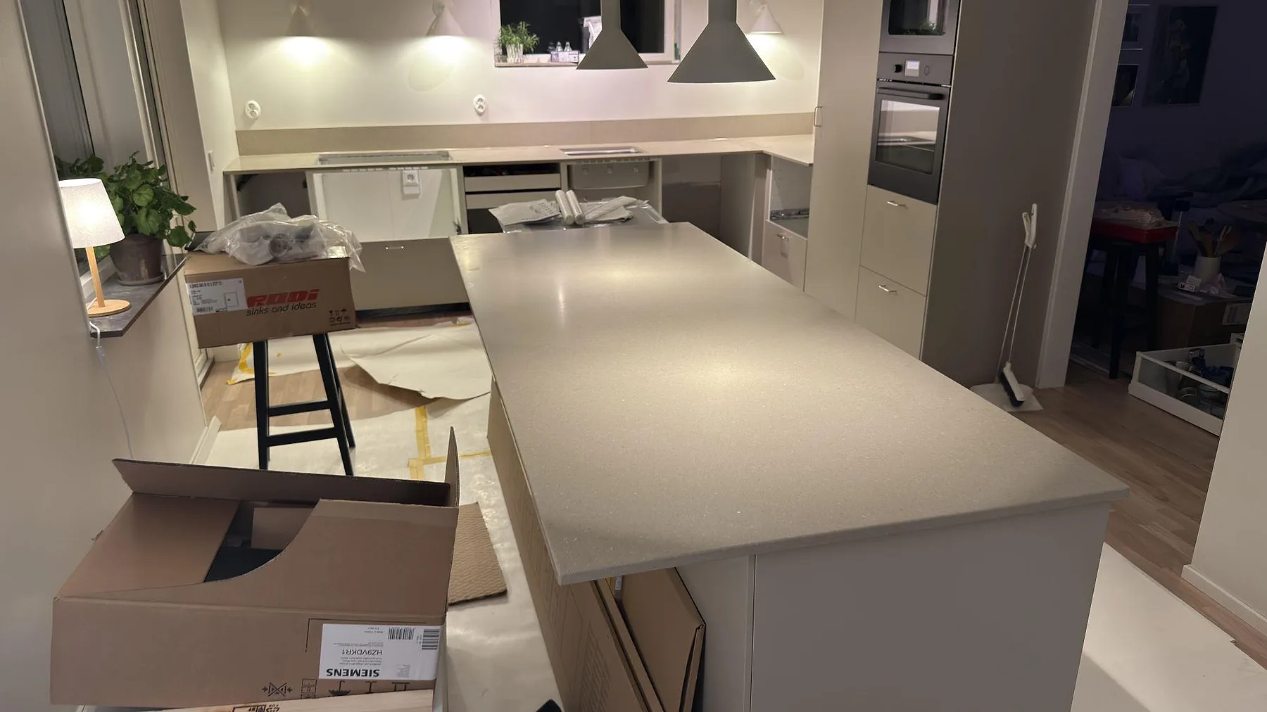 Stor köksö i Caesarstone Shitake, matt brun kvartskomposit, med bänkrad i bakgrunden under montering i ett kök i Örebro.