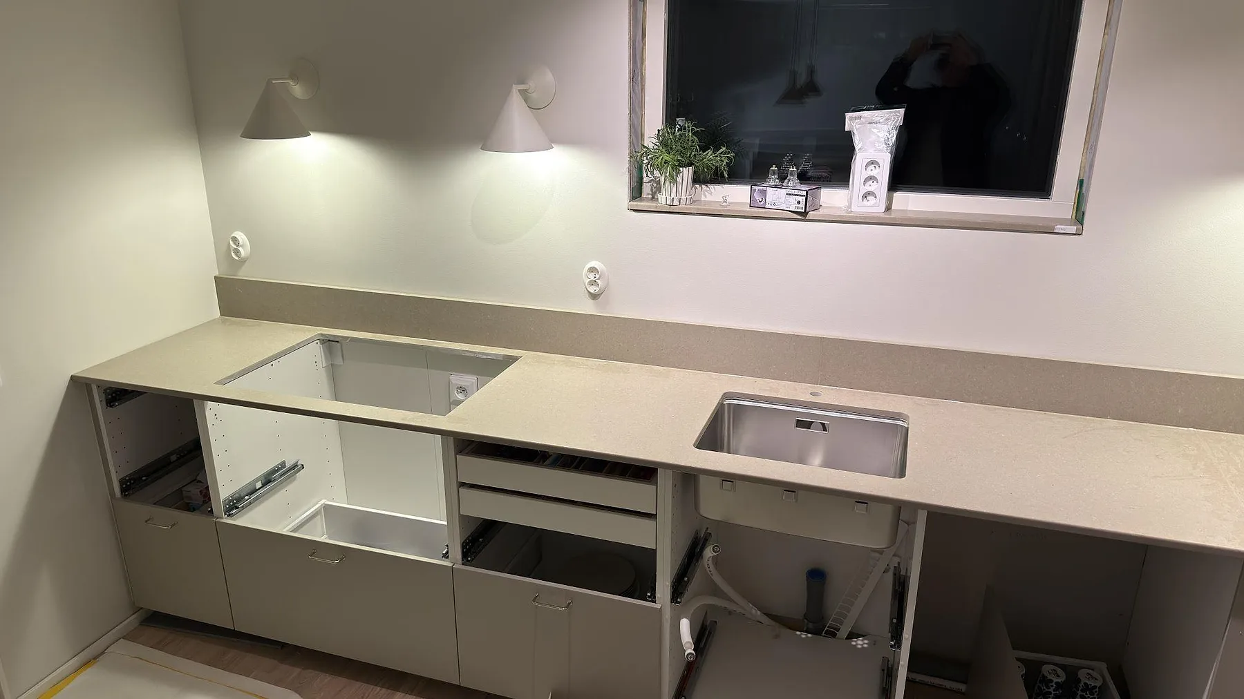 Köksbänkskiva i Caesarstone Shitake, matt taupebrun kvartskomposit, med underlimmad rostfri diskho och urtag för häll längs en L-formad bänk i ett kök i Örebro.