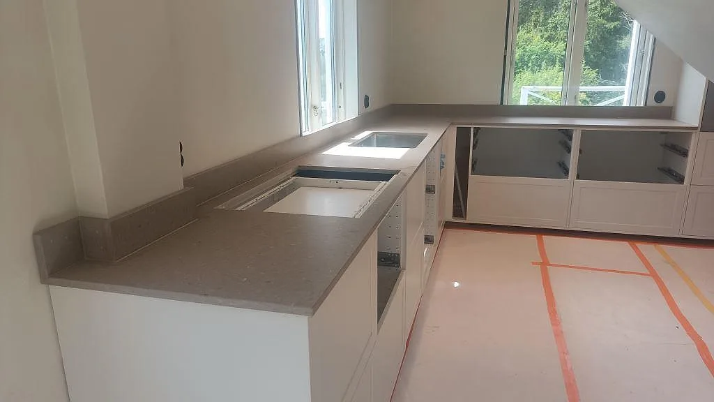 Köksbänkskiva i Caesarstone Shitake komposit, matt, i L-format med underlimmad diskho och hällöppning i Sandared.