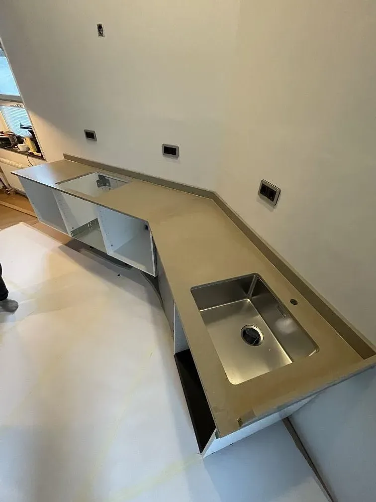Köksbänkskiva i Caesarstone Shitake, matt, på en L-formad köksdel med underlimmad rostfri diskho i ett kök under montering i Stockholm.