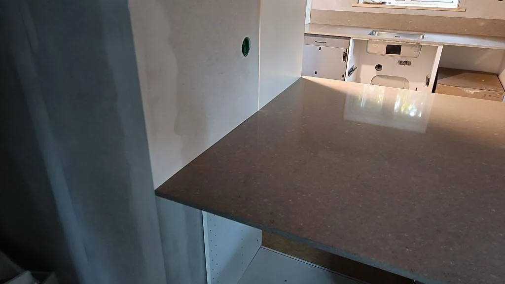 Polerad Caesarstone Shitake på köksö med bänksträckan och låg stänkkant i bakgrunden i ett kök i Västra Frölunda.