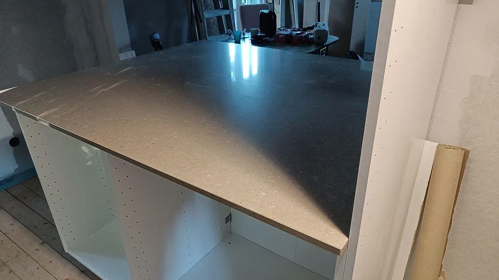 Polerad köksöskiva i Caesarstone Shitake sedd från sidan, med ljusreflexer över den spräckliga kvartskompositen i Västra Frölunda.