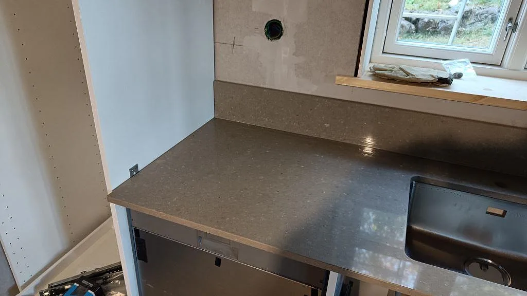 Bänkskiva i Caesarstone Shitake med låg uppvikt stänkkant och synlig rostfri diskho under montering i Västra Frölunda.