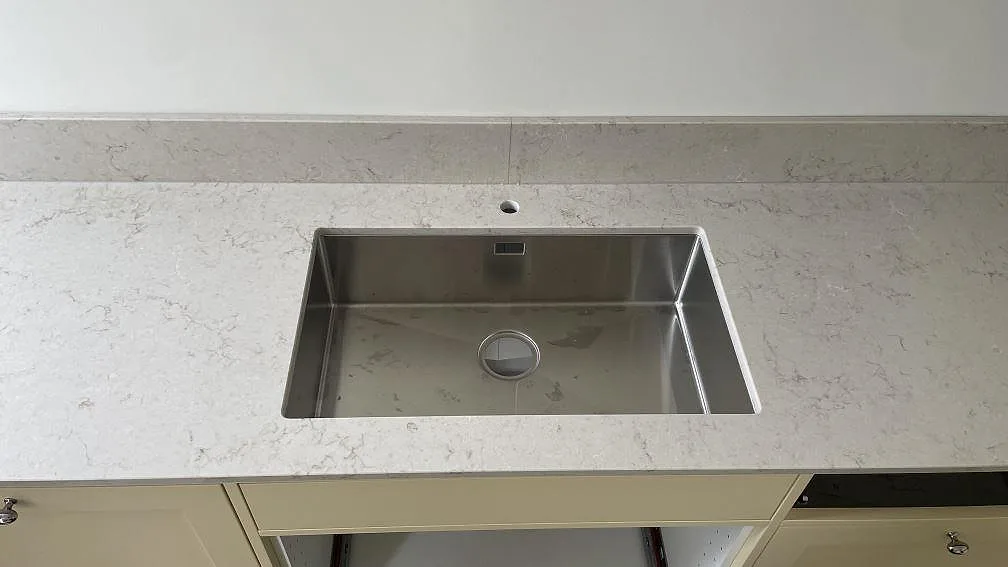 Polerad köksbänkskiva i Caesarstone Taj Royale 5212 med rostfri diskho och låg stänkkant i ett kök i Höllviken.