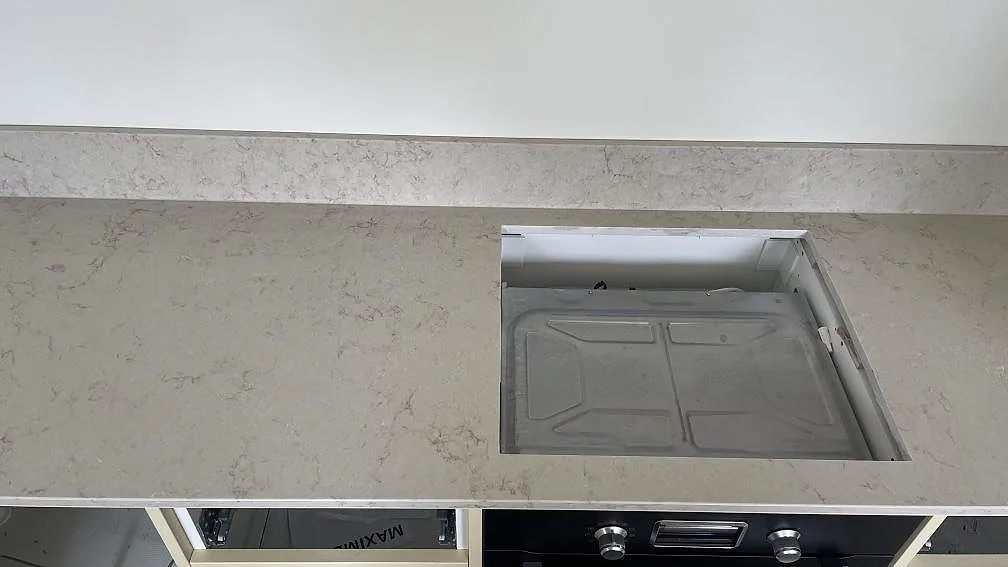 Bänkskiva i polerad Caesarstone Taj Royale 5212 med förberett hällurtag, låg stänkkant och ugn i kök i Höllviken.