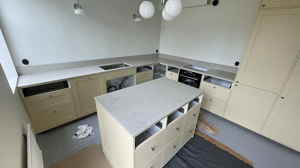 Köksbänkskiva och köksö i polerad Caesarstone Taj Royale 5212, ljus kvartskomposit med låg stänkkant i ett kök i Höllviken.