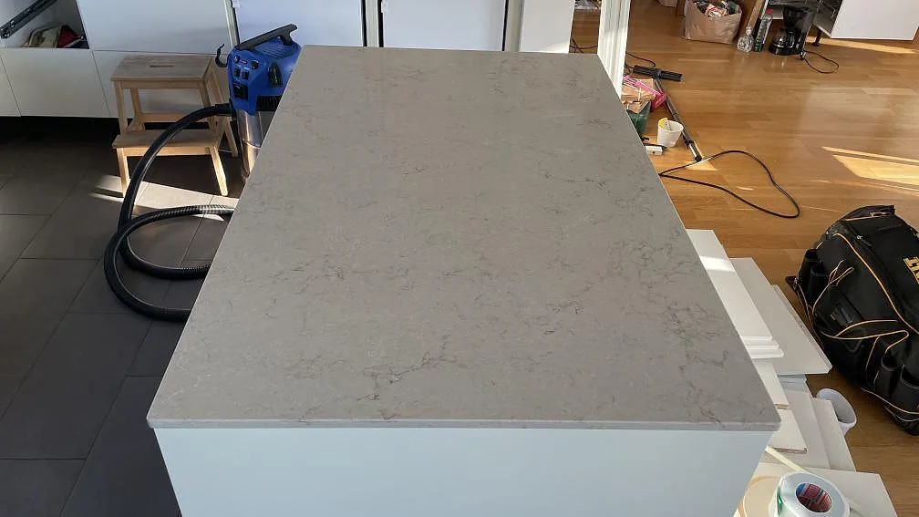 Toppskiva på köksö i polerad Caesarstone Taj Royale 5212, med ljus kvartskomposit och marmorlik ådring i Lomma.