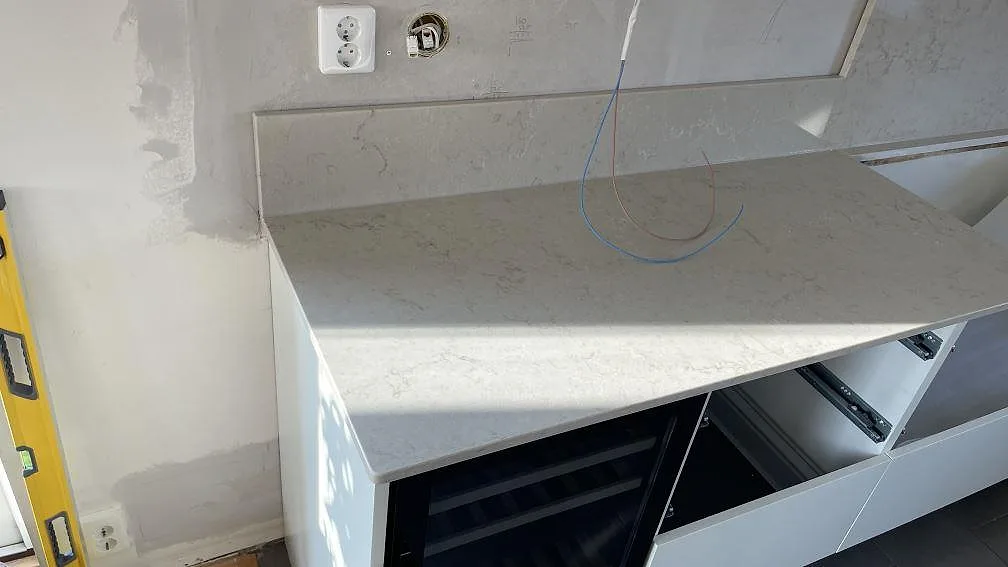 Väggbänk i polerad Caesarstone Taj Royale 5212 med lågt stänkskydd och förberett hällurtag i ett kök i Lomma.