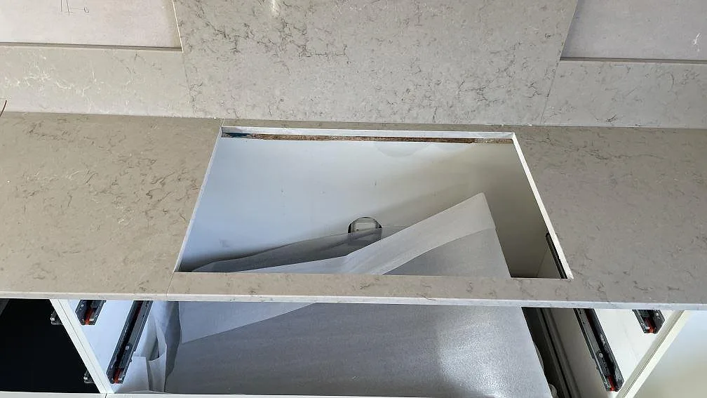 Detalj av diskhourtag i polerad Caesarstone Taj Royale 5212, med matchande stänkskydd i ett kök i Lomma.