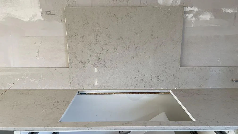 Bänkskiva i Caesarstone Taj Royale 5212 med diskhourtag och polerade stänkskyddsplattor under montering i Lomma.