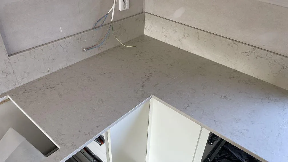 L-formad köksbänkskiva i Caesarstone Taj Royale 5212, polerad komposit med stänkskydd och urtag i Lomma.