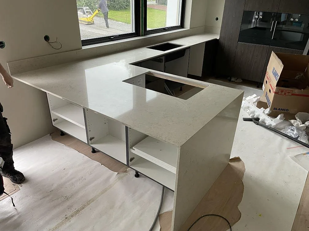 Köksbänkskiva och köksdel i Caesarstone Taj Royale 5212, polerad komposit, med låg stänkkant och öppna stommar i Nacka.