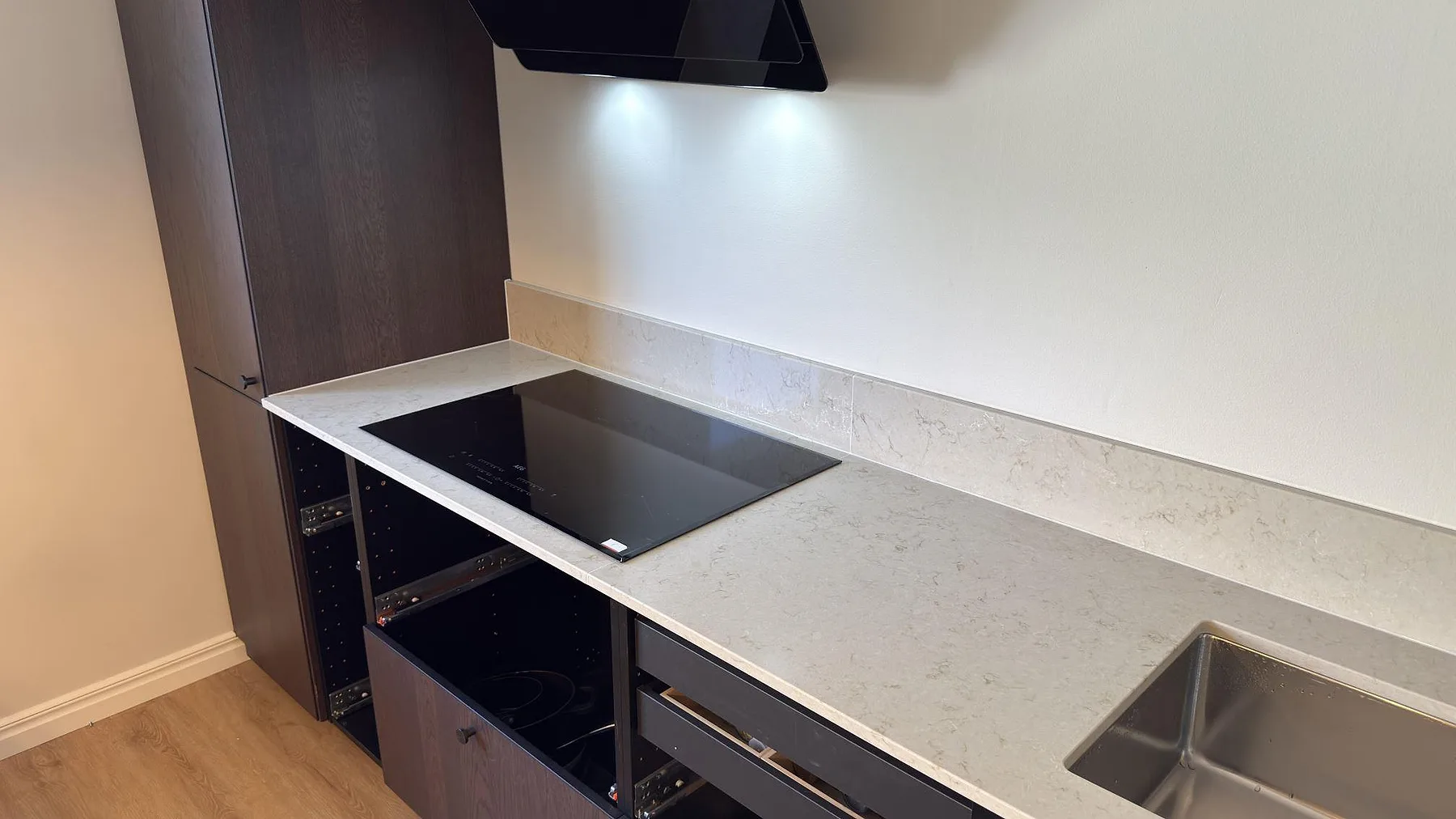 Induktionshäll infälld i polerad bänkskiva av Caesarstone Taj Royale 5212 med låg uppvikt stänkkant i ett kök i Norrköping.