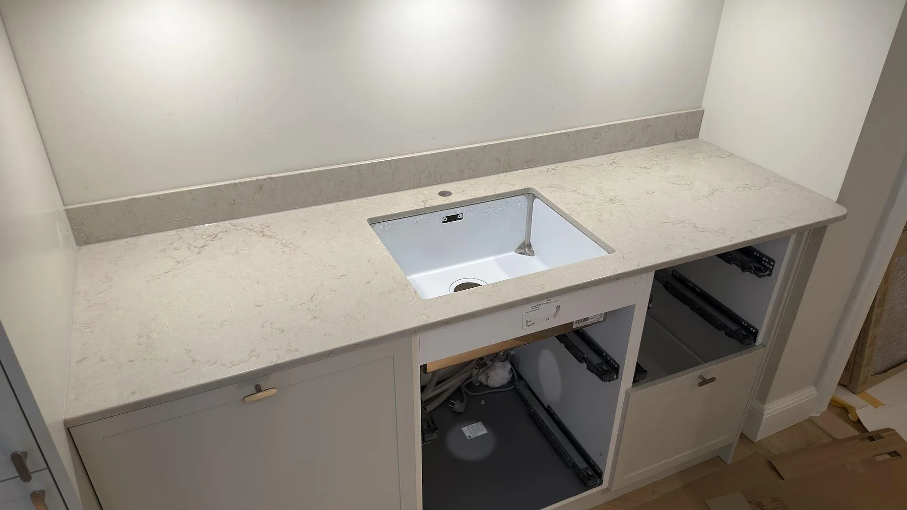 Bänkskiva i Caesarstone Taj Royale 5212, polerad komposit, med låg stänkkant och diskhozon i ett kök i Stockholm.