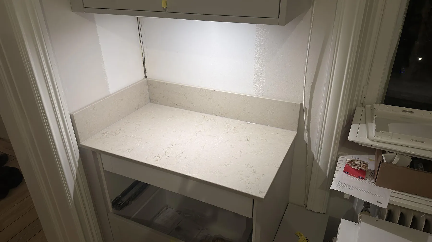 Närbild på köksbänkskiva i Caesarstone Taj Royale 5212 med mjuk guld och grå ådring och uppvikt stänkkant vid fönstret i ett kök i Stockholm.