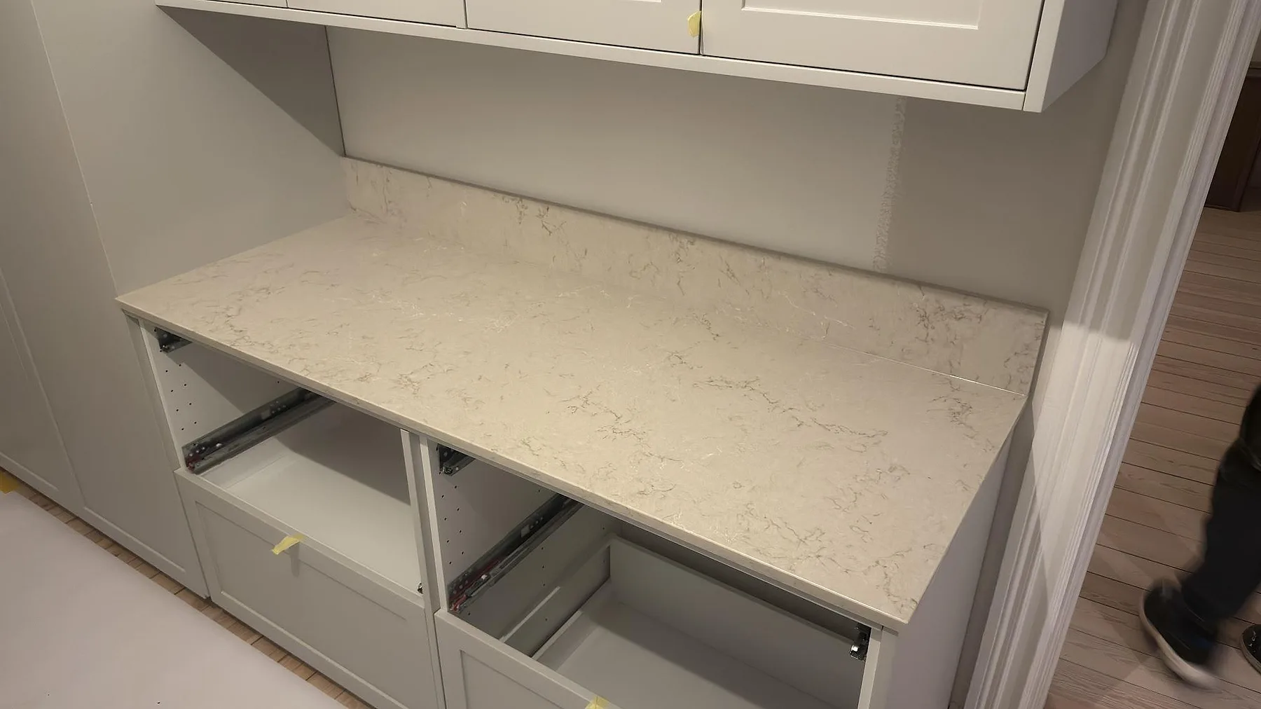 Polerad bänkskiva i Caesarstone Taj Royale 5212 med uppvikt stänkkant mot grå shakerluckor i ett kök i Stockholm, fotad innan rummet var helt inrett.