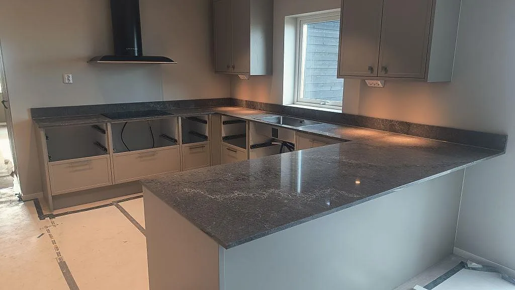 Köksbänkskiva i polerad Caesarstone Turbine Grey, komposit, med U-form och peninsula i ett kök i Alingsås.