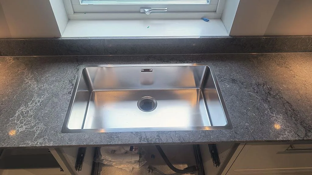 Rostfri underlimmad diskho i en polerad Caesarstone Turbine Grey bänkskiva med stänkkant i Alingsås.