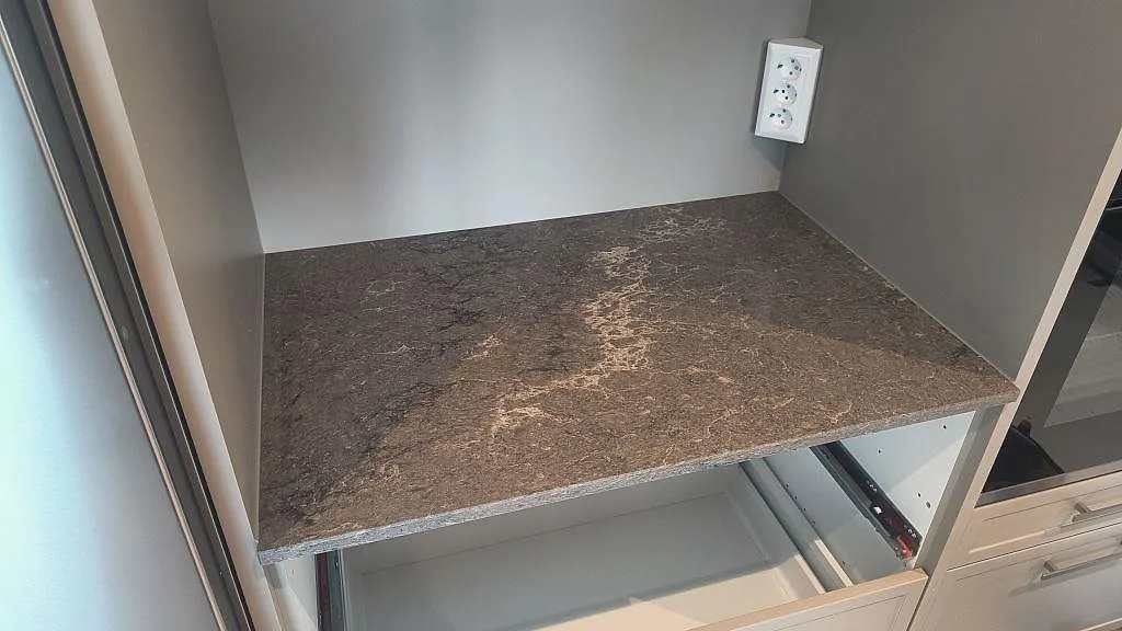 Installerad bänkskiva i polerad Caesarstone Turbine Grey i ljus köksstomme intill fönster i Alingsås.