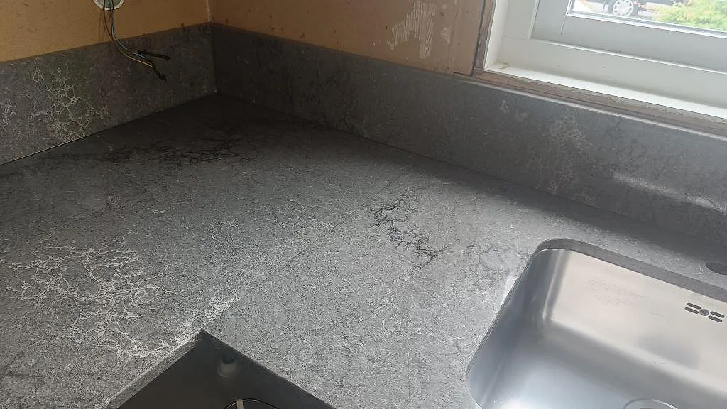 Köksbänkskiva i polerad Caesarstone Turbine Grey, grå komposit, med underlimmad rostfri diskho under fönster i Bredaryd.