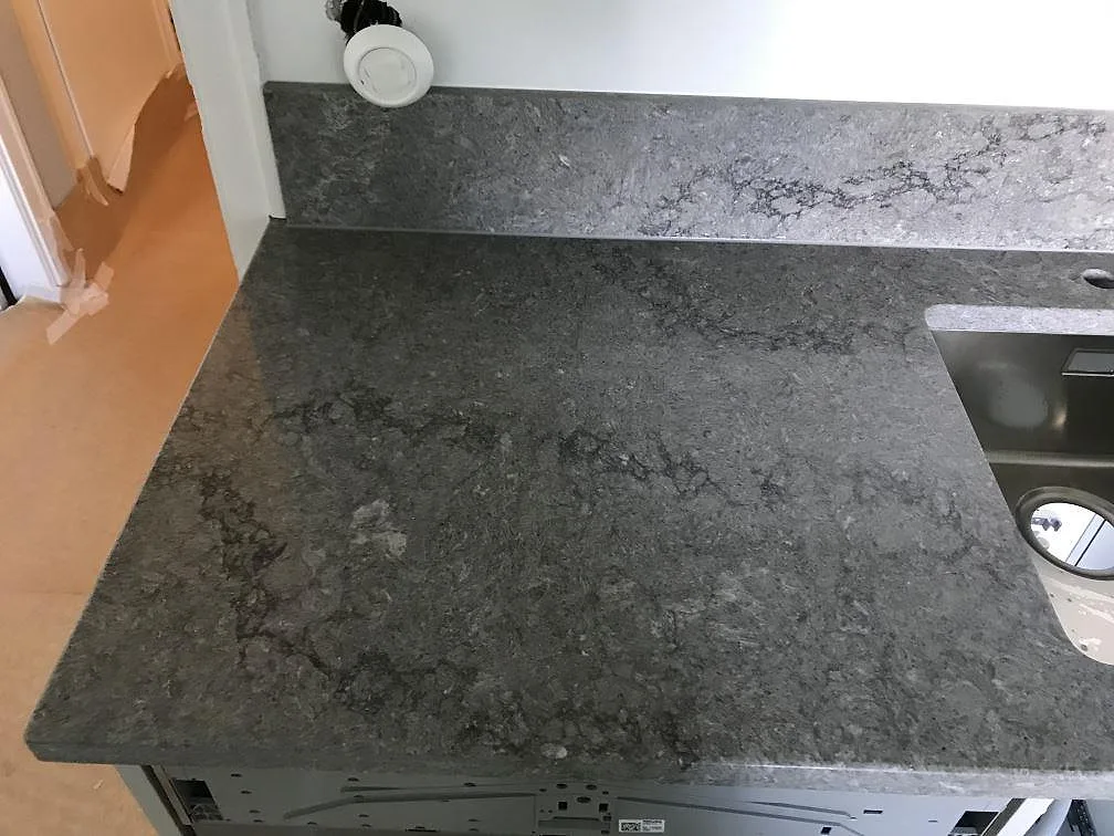 Bänkskiva i Caesarstone Turbine Grey med urtag för häll och rörelse i den polerade mörkgråa ytan i ett kök i Göteborg.