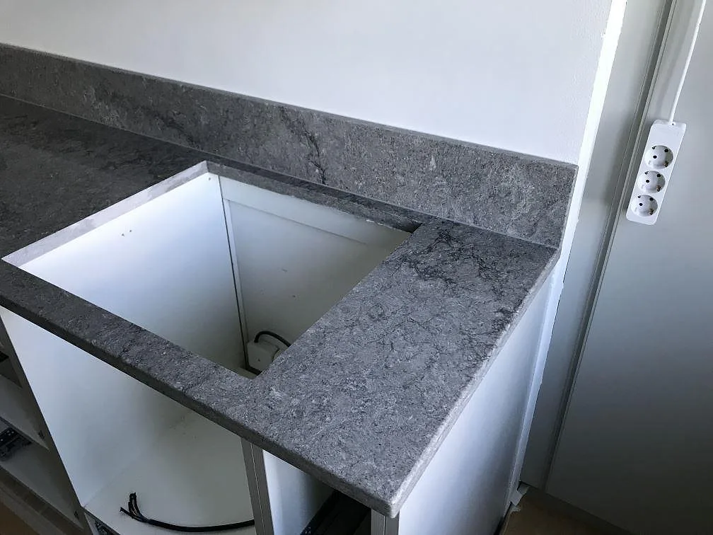 Köksbänkskiva i mörkgrå Caesarstone Turbine Grey med urtag för diskho och öppna skåpsstommar under montering i ett kök i Göteborg.
