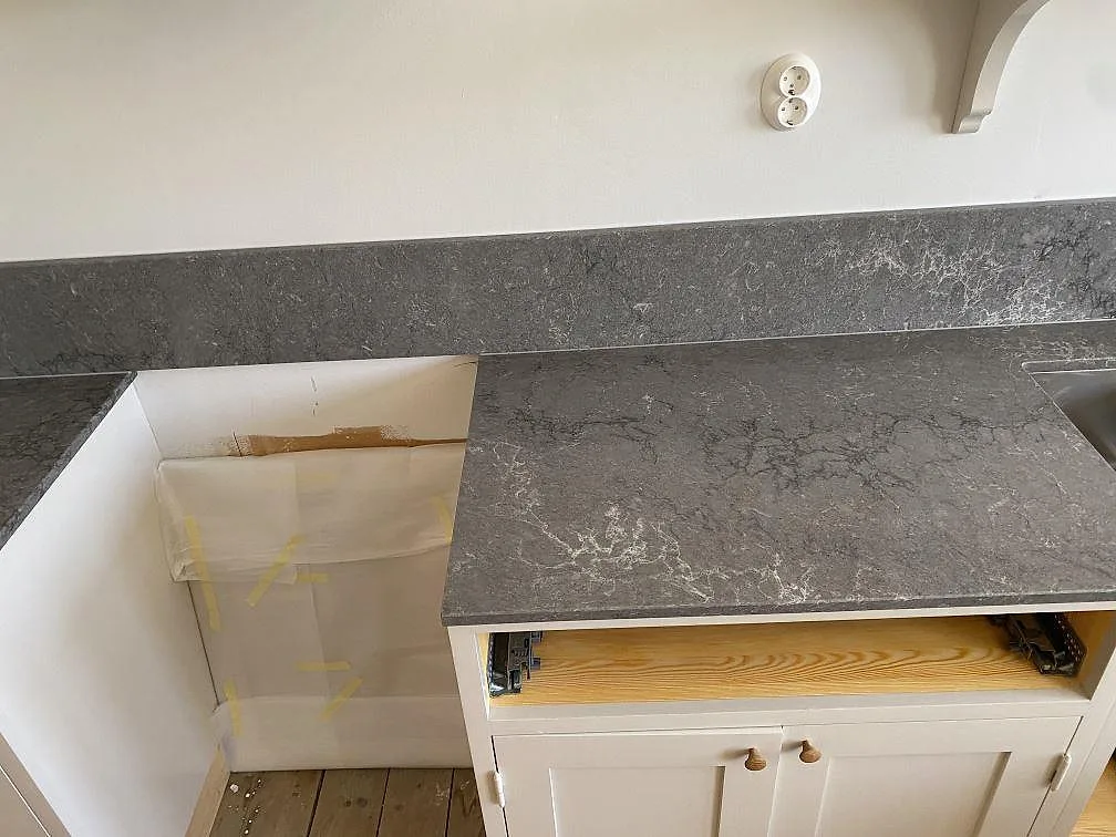 Polerad köksbänkskiva i Caesarstone Turbine Grey med underlimmad rostfri diskho och stänkskydd i samma sten i ett kök i Göteborg.