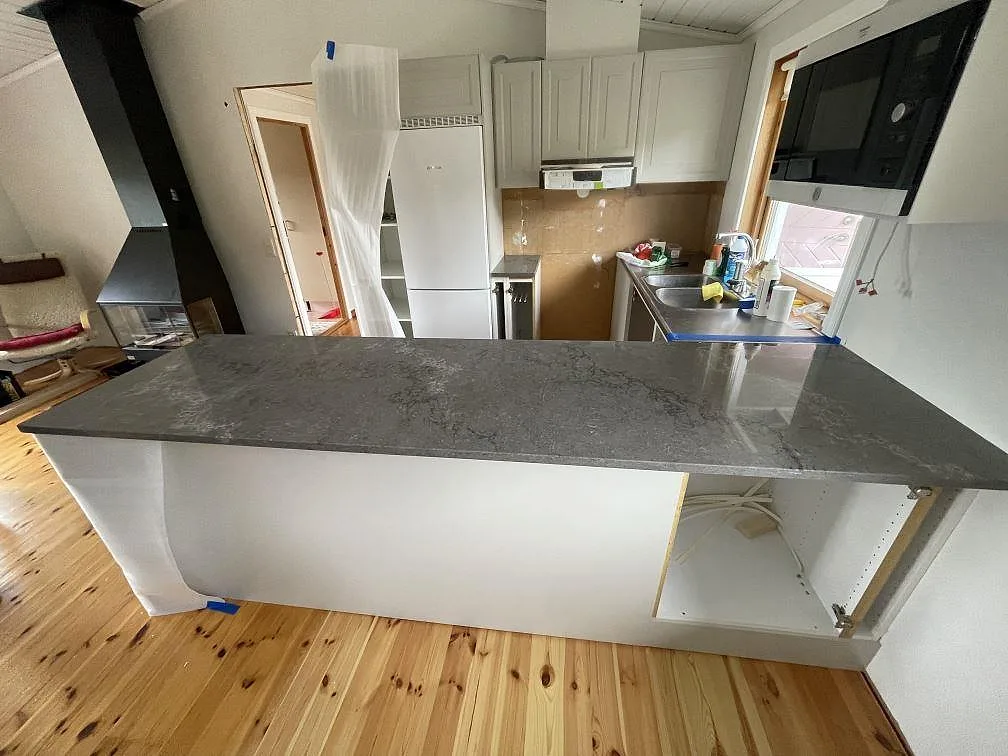 Köksbänkskiva i polerad Caesarstone Turbine Grey, grå komposit, på en bred halvö i ett kök i Grundsund.