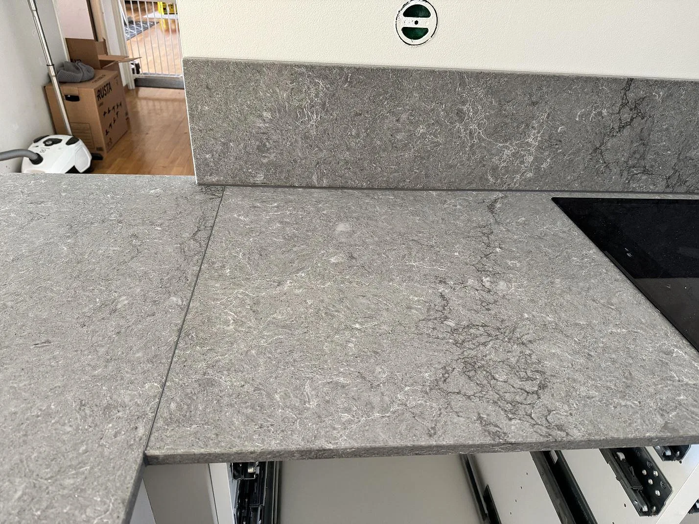 Närbild på polerad Caesarstone Turbine Grey med stänkkant, häll och tydlig grå ådring i köket i Halmstad.