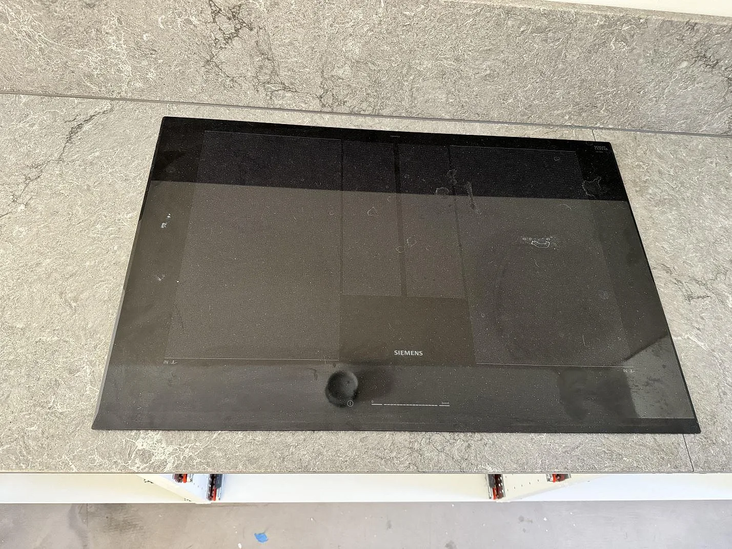 Svart häll infälld i köksbänkskiva av polerad Caesarstone Turbine Grey, grå kvartskomposit, i ett kök i Halmstad.