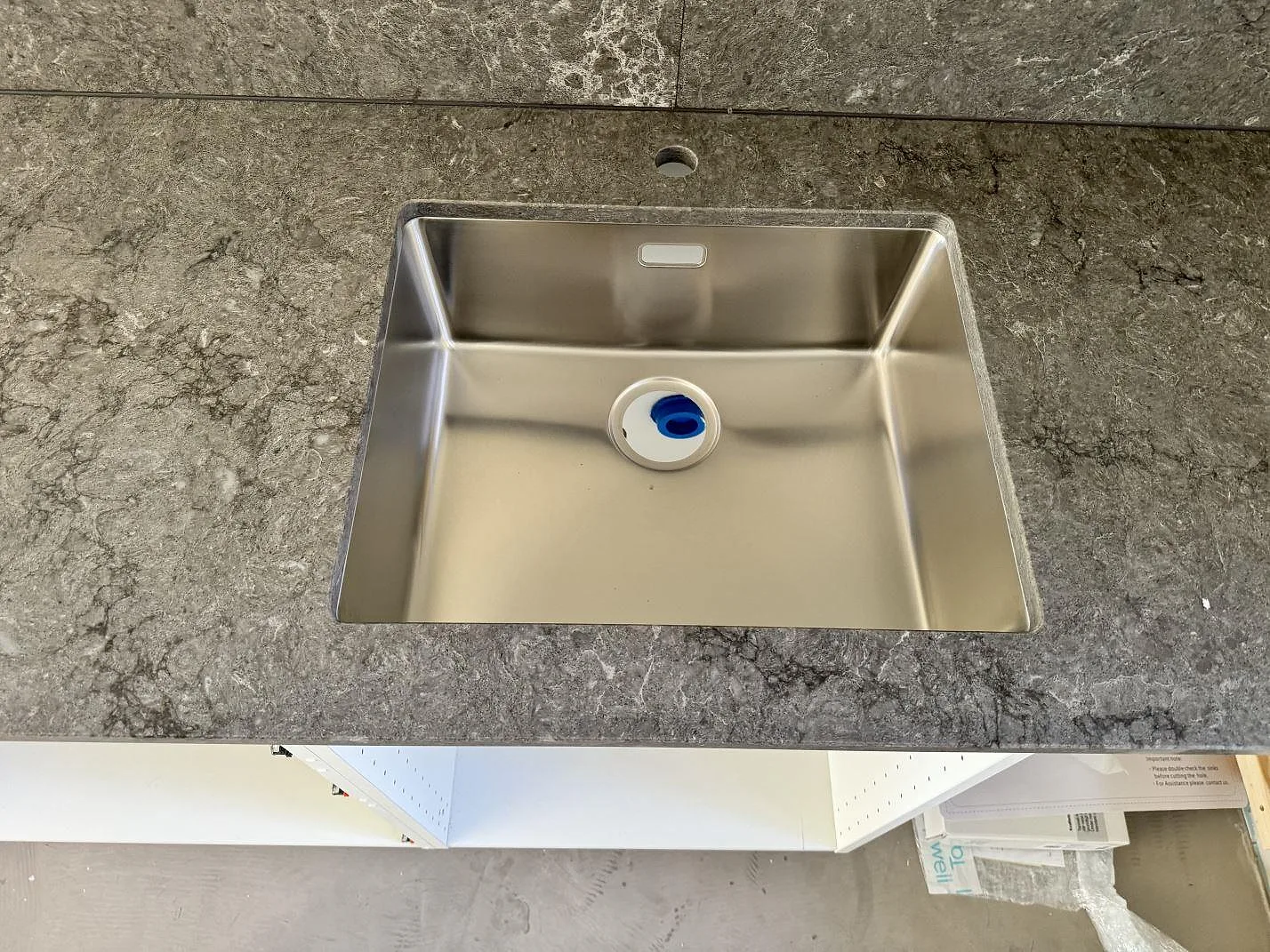 Underlimmad rostfri diskho i polerad Caesarstone Turbine Grey med grå ådring och uppvikt stänkkant i ett kök i Halmstad.