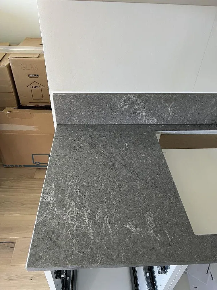 Närbild på grå Caesarstone Turbine Grey i polerad komposit med marmorerad ådring och urtag för diskho i kök i Helsingborg.