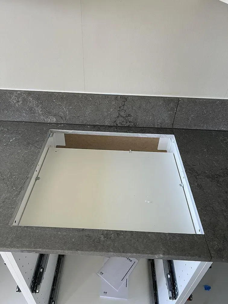 Sinkuttag i polerad Caesarstone Turbine Grey med grå ådring och vit köksstomme under montering i Helsingborg.