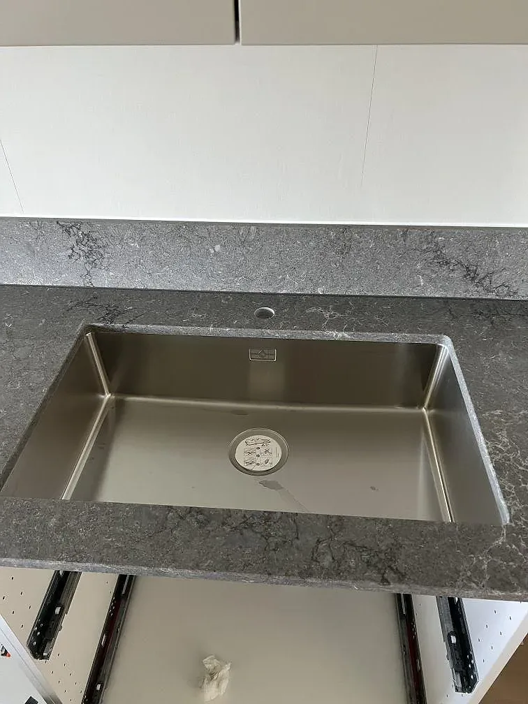 Underlimmad rostfri diskho i Caesarstone Turbine Grey, polerad grå kompositbänkskiva i ett kök i Helsingborg.