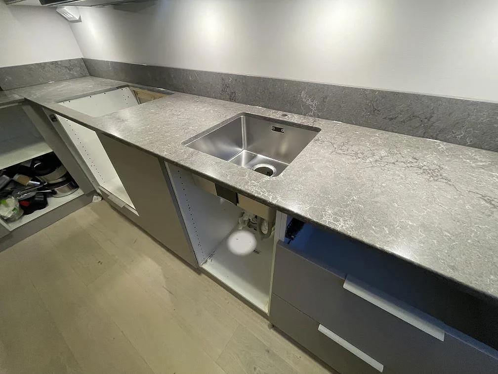 Polerad köksbänkskiva i Caesarstone Turbine Grey med underlimmad rostfri diskho och mjuk vit ådring i ett kök i Stockholm.