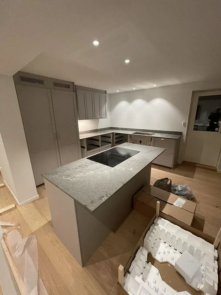 Köksbänkskiva i polerad Caesarstone Turbine Grey med grå ådring på köksö under montering i Västra Frölunda.