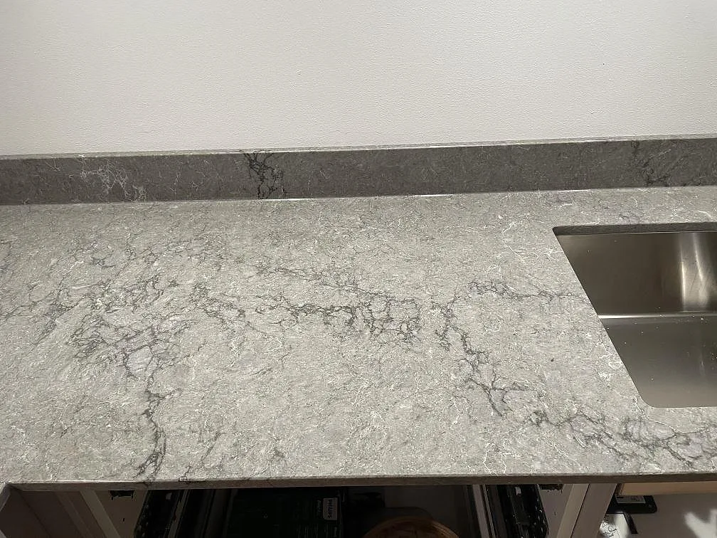 Närbild på polerad Caesarstone Turbine Grey med vit ådring och rostfri diskho i ett kök i Västra Frölunda.