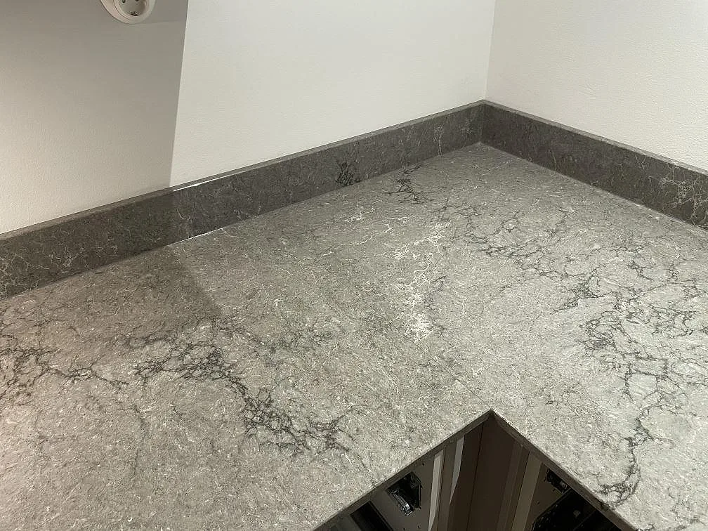 Hörn av köksbänkskiva i Caesarstone Turbine Grey med uppvikt stänkkant i ett kök i Västra Frölunda.