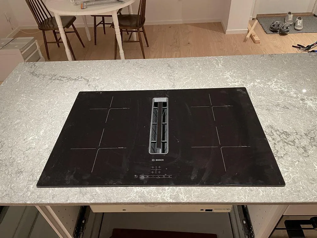 Köksbänkskiva i Caesarstone Turbine Grey med infälld Bosch induktionshäll med integrerad fläkt i ett kök i Västra Frölunda.