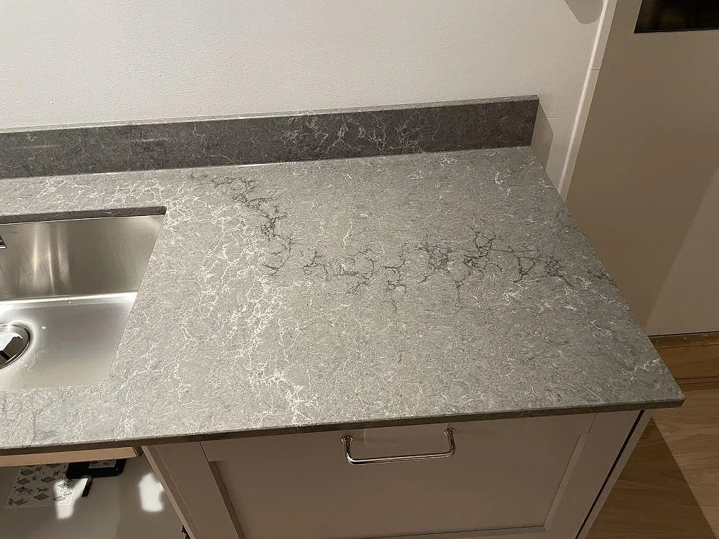 Köksö i polerad Caesarstone Turbine Grey sedd ovanifrån med svart induktionshäll i ett kök i Västra Frölunda.