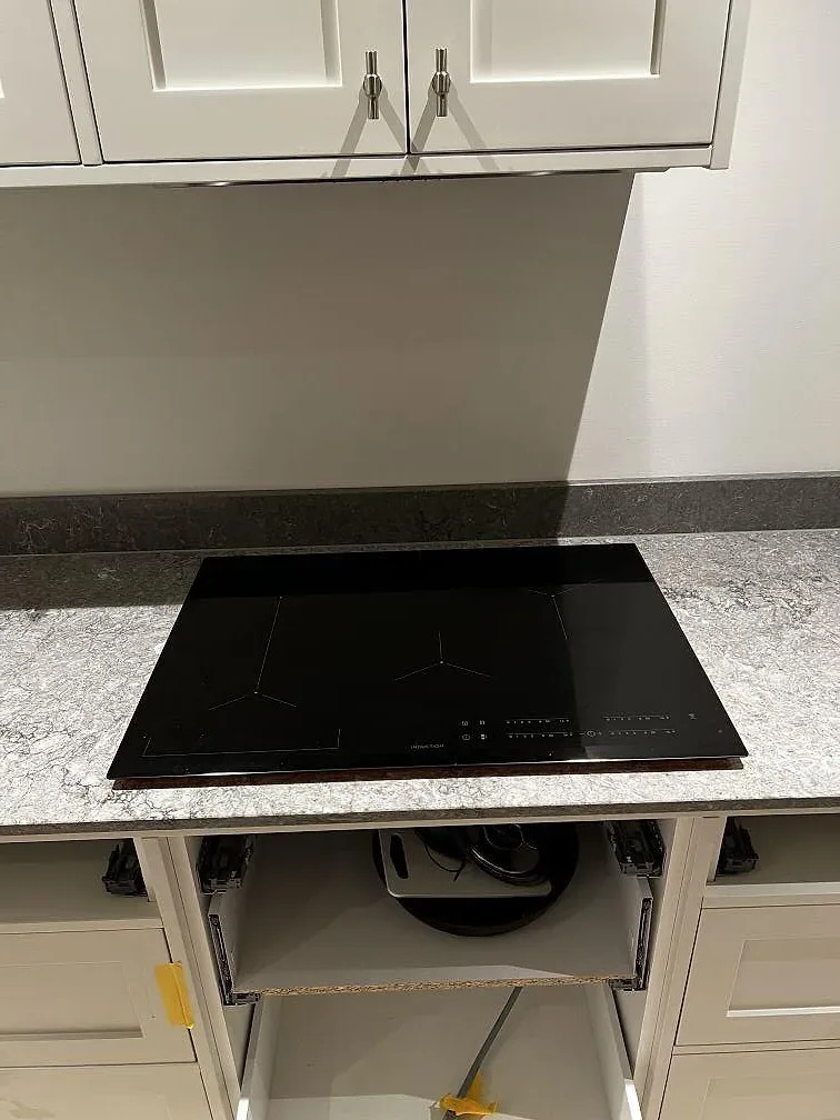 Induktionshäll som monteras i en grå köksbänkskiva i Caesarstone Turbine Grey under pågående köksmontering i Västra Frölunda.
